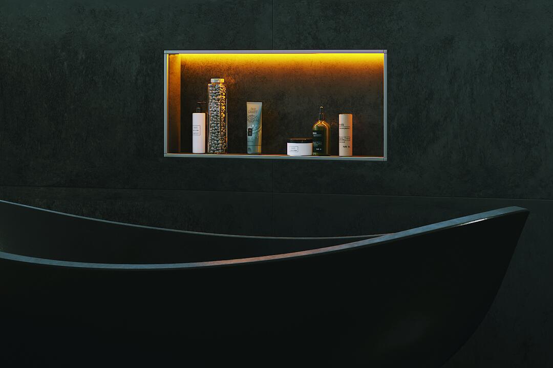 Eine in eine schwarze Wand eingelassene, orange beleuchtete Duschablage mit mehreren Pflegeprodukten.