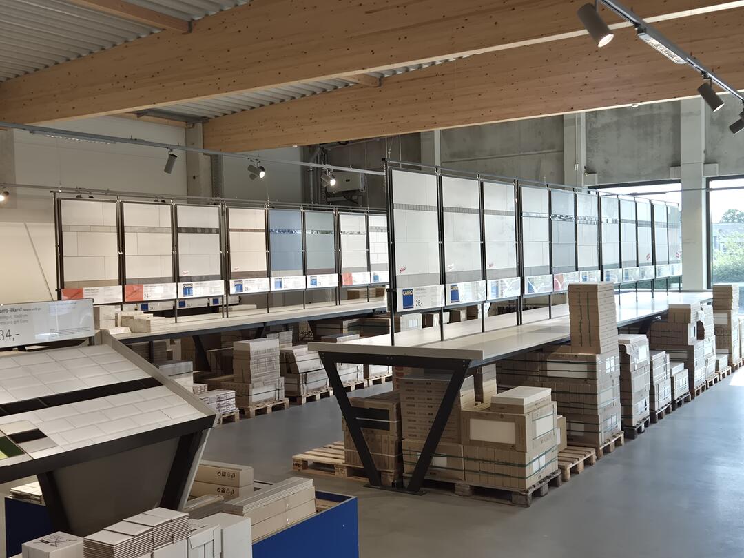 Ausschnitt einer Fliesenausstellung mit mittelgroßen Fliesen in hellen Beige-Tönen.