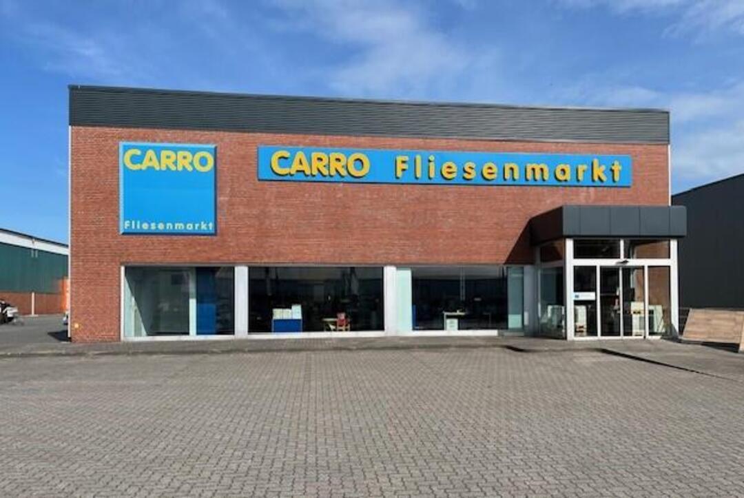 Der CARRO Fliesenmarkt in Husum, ein einfaches rotes Ziegelgebäude mit Flachfach und dem dazugehörigen großen Schriftzug in den Unternehmensfarben blau und gelb.